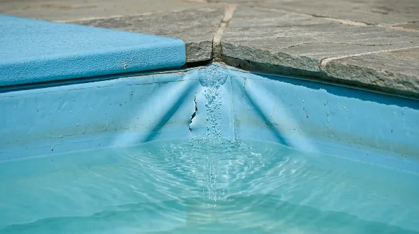 Fissure dans un liner de piscine bleu, signe d'une fuite d'eau